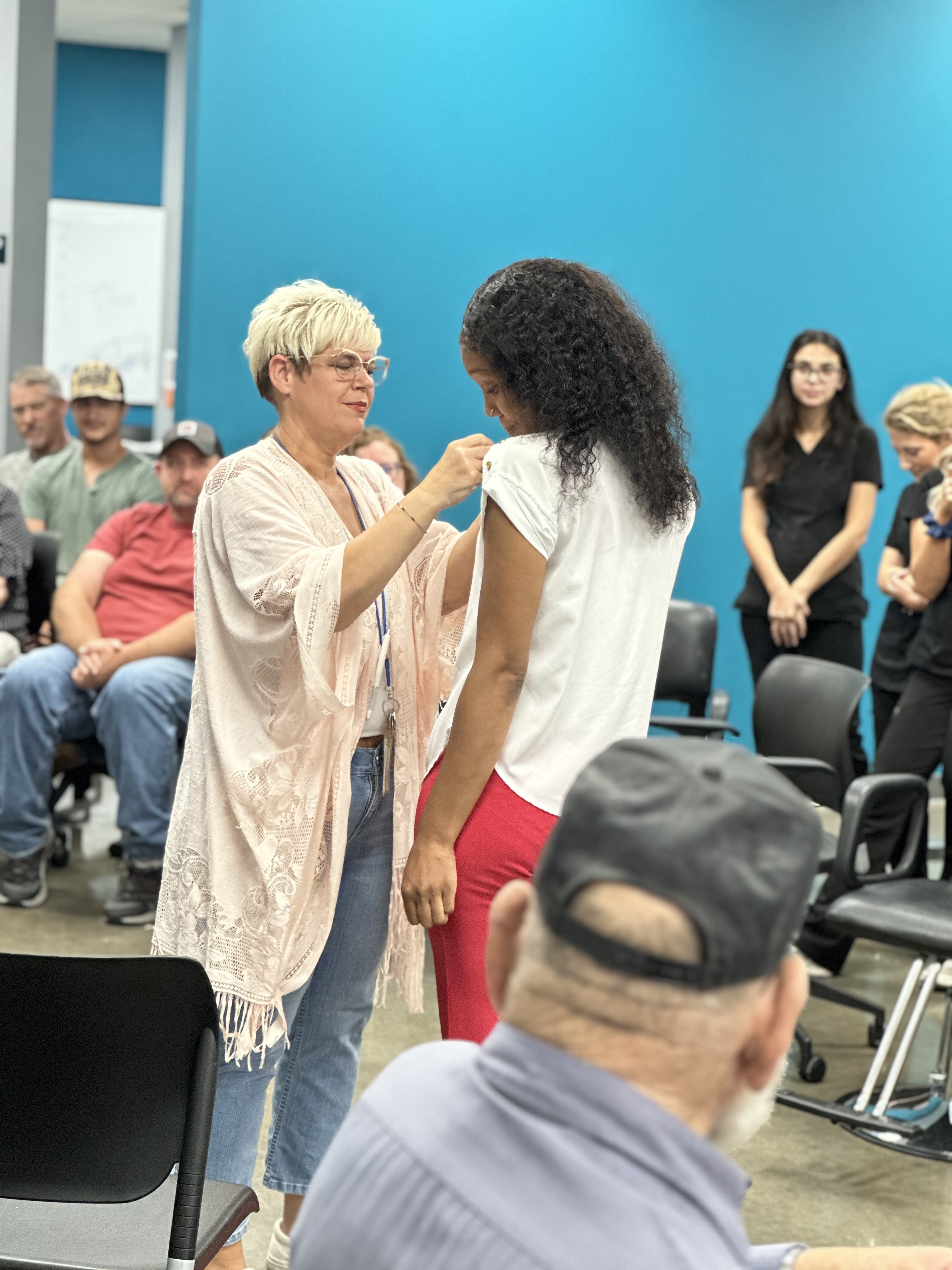 Cosmetology Instructor Placing Pin on Student