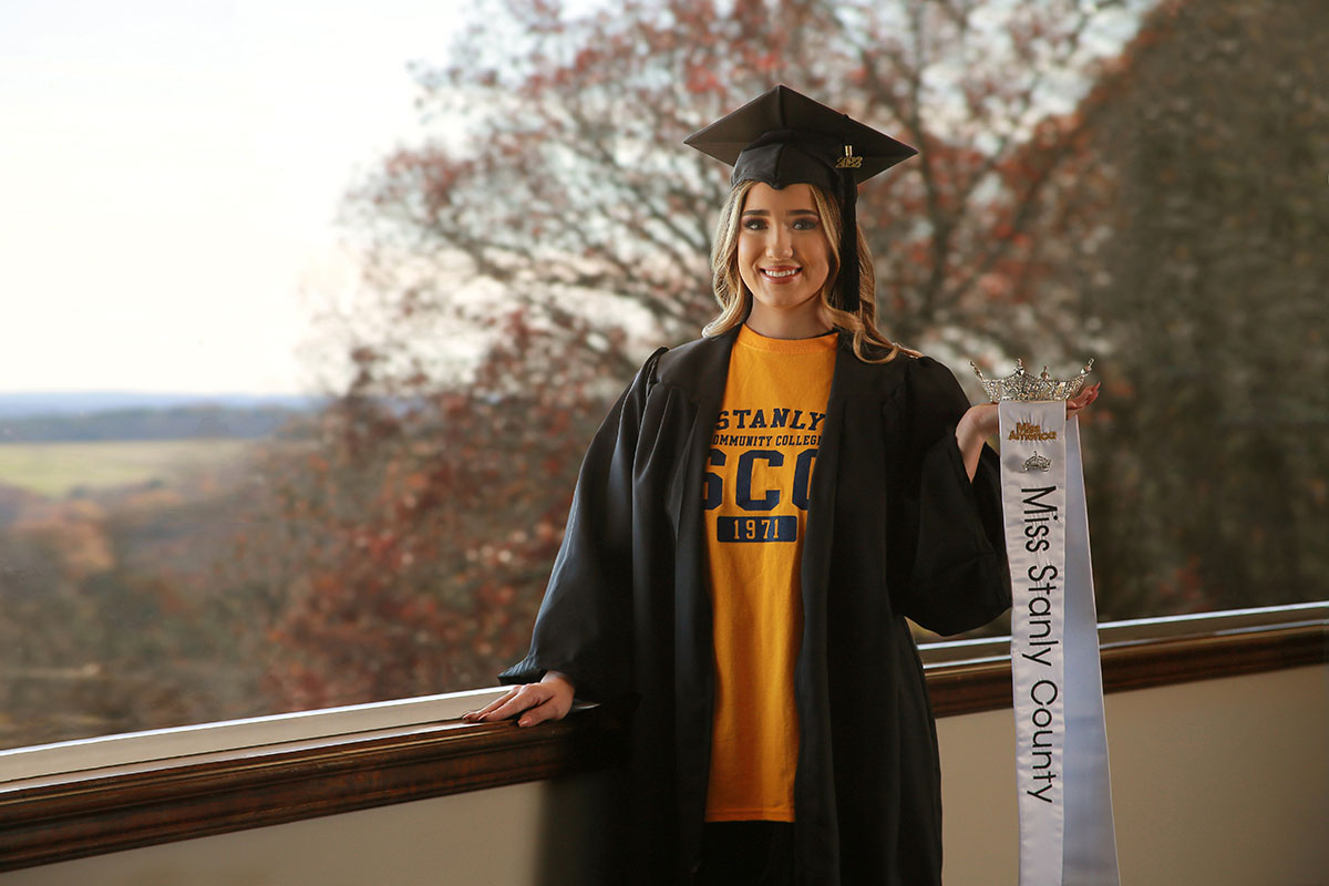 Female graduate holding Miss Stanly County crown and sash