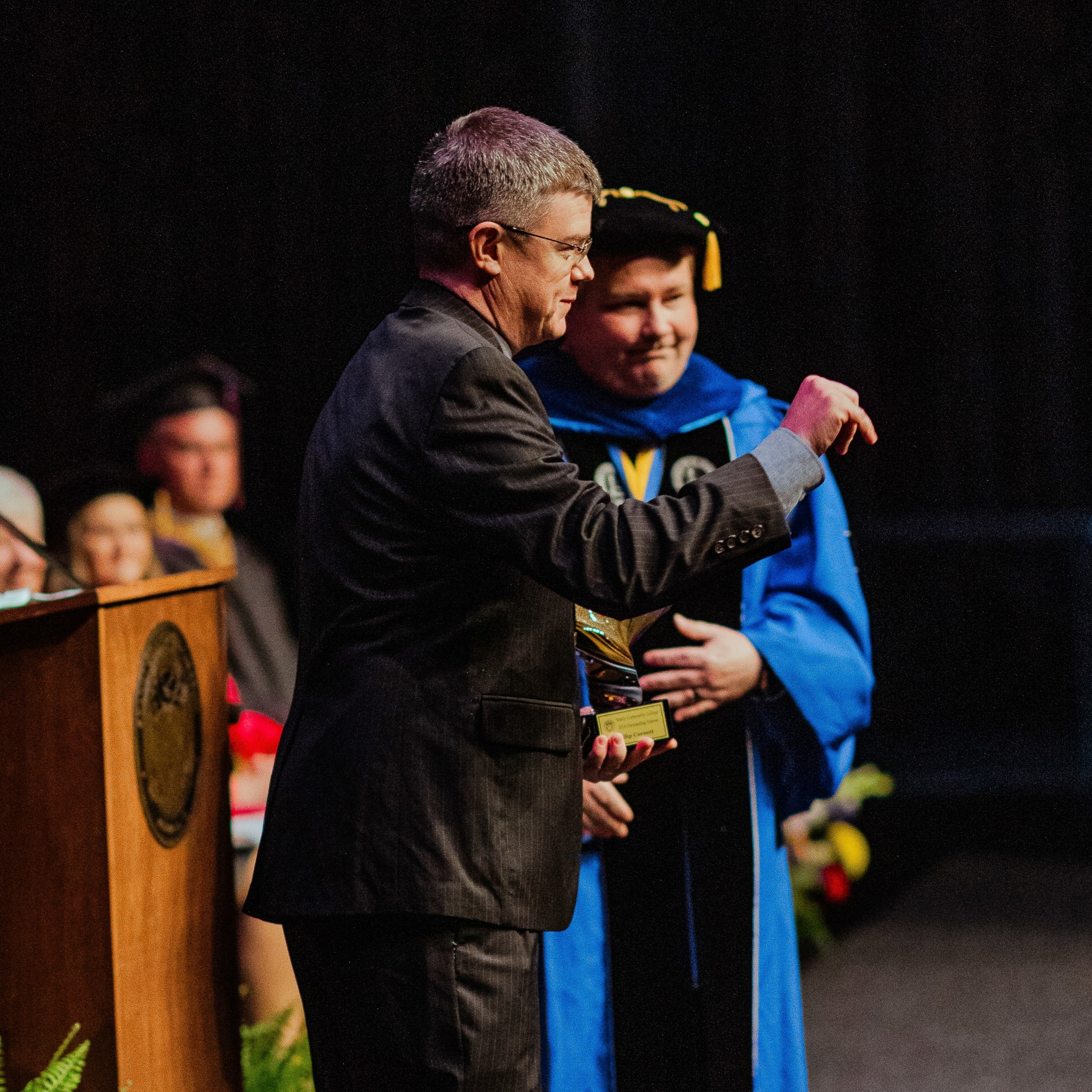 Stanly Community College alumni in grey suit turns to face the audeince as he receives the Outstanding Alumni Award.