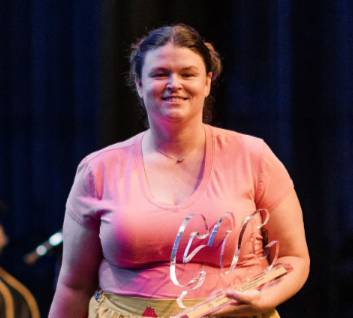 femail in pink shirt on stage carrying award