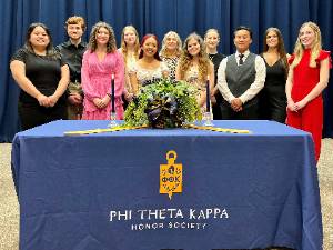 SCC students standing in front of table with Phi Theta Kappa logo