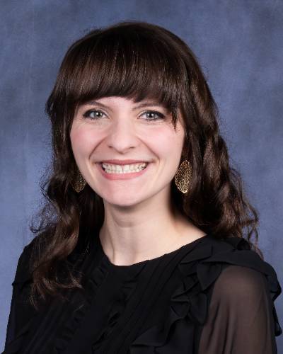 Female with dark brown hair and black shirt smiling