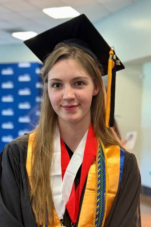 Female in graduation cap and gown smiling at camera