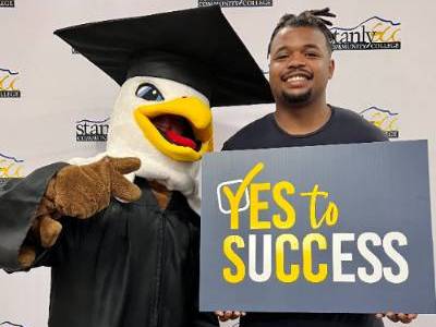 mascot and male student holding sign