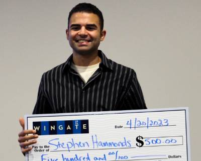 Male Student Holding Large Check for Third Place Finish in Shark Tank Competition