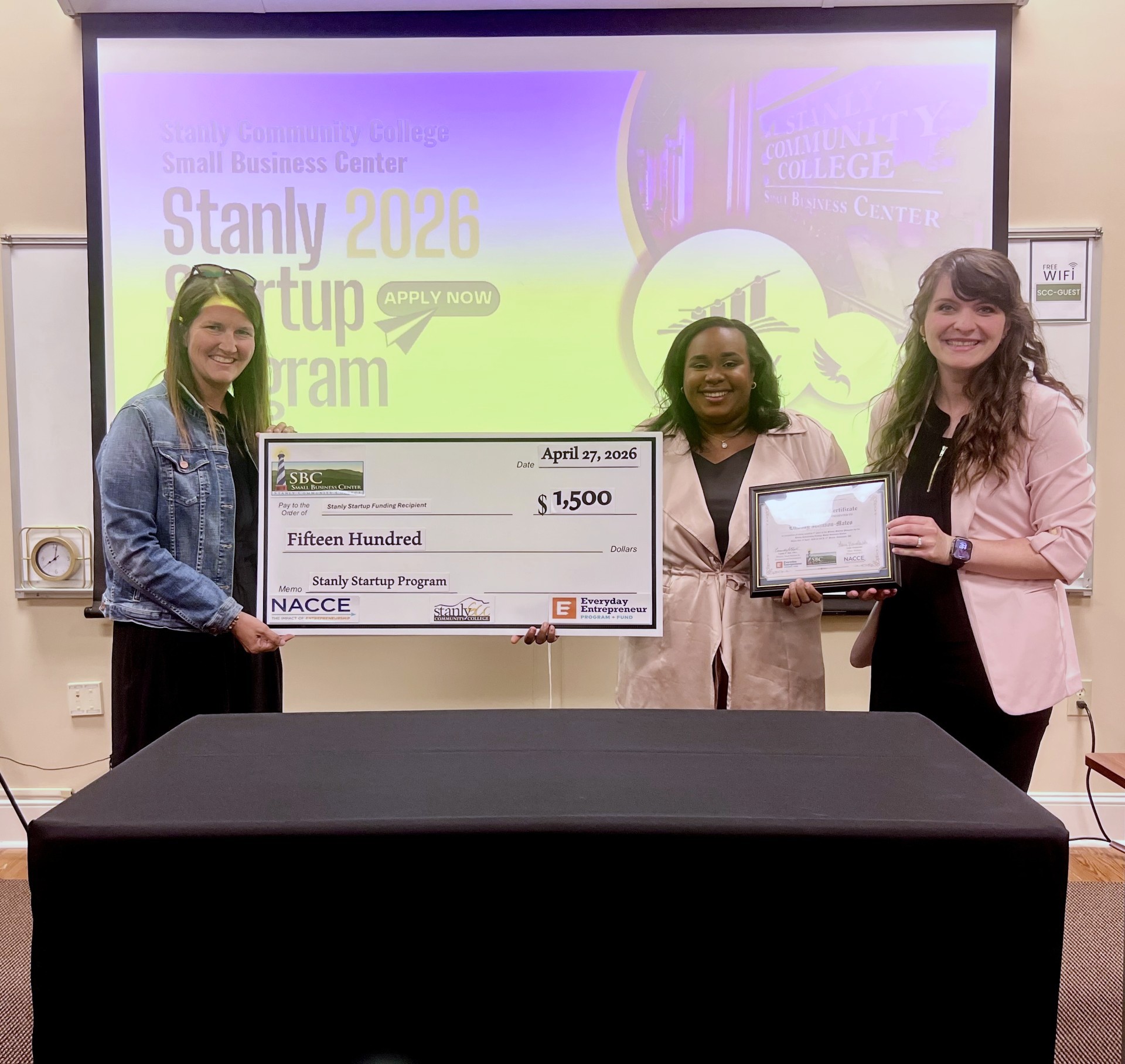Two Stanly Community College employees award local small business owner with prize money.